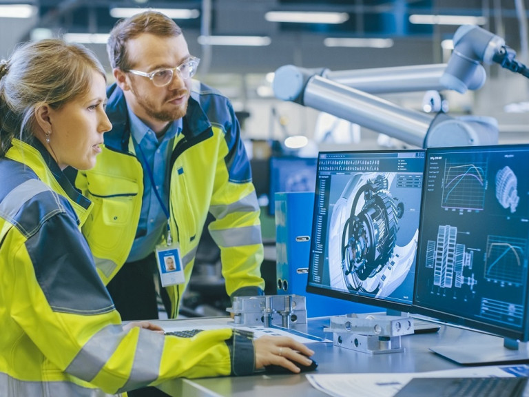 At the Factory: Male Mechanical Engineer and Female Chief Engineer Work Together on the Personal Computer, They Discuss Details of the 3D Engine Model for Robotic Arm.