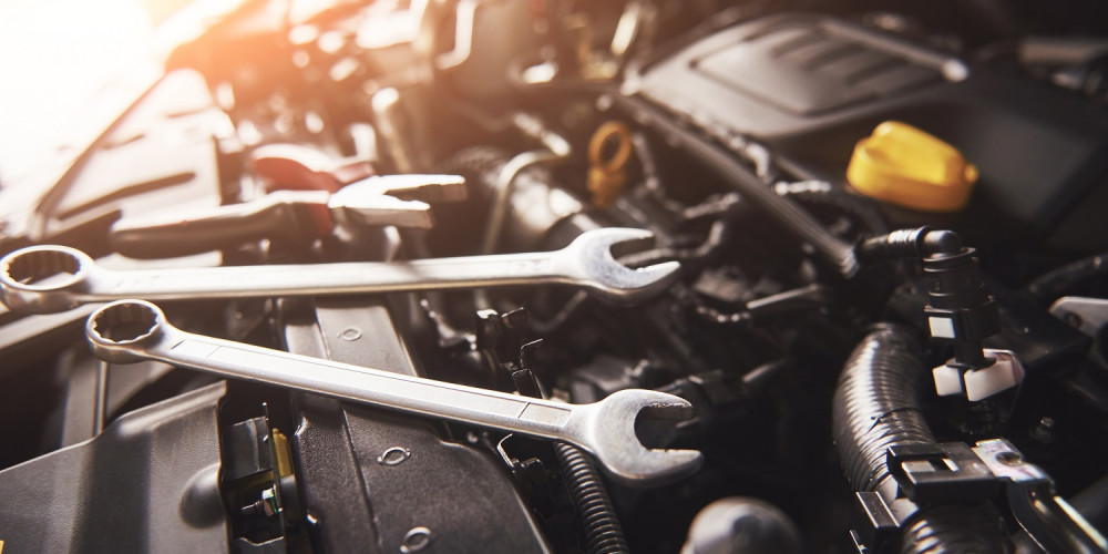 Mechanic hand checking and fixing a broken car in car service garage